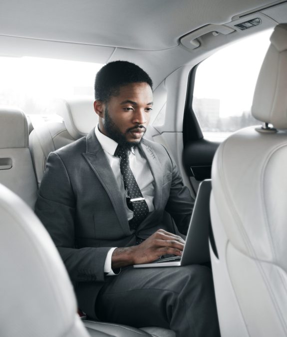 Always available. Handsome businessman working on laptop, sitting in car on back seat